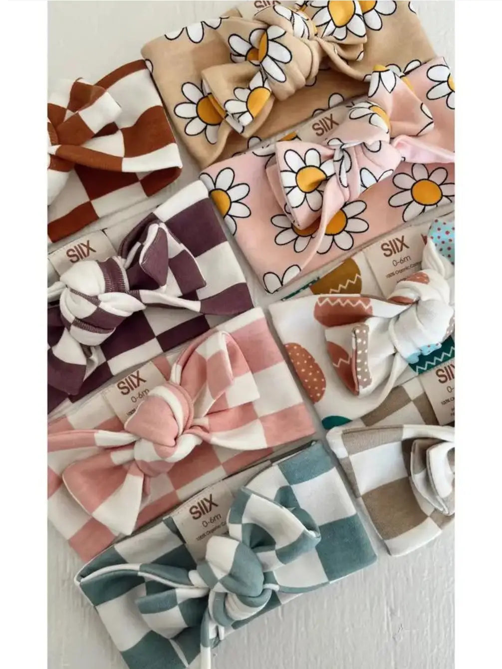 Assorted baby headbands featuring various colors and patterns, including florals and checks, displayed neatly.
