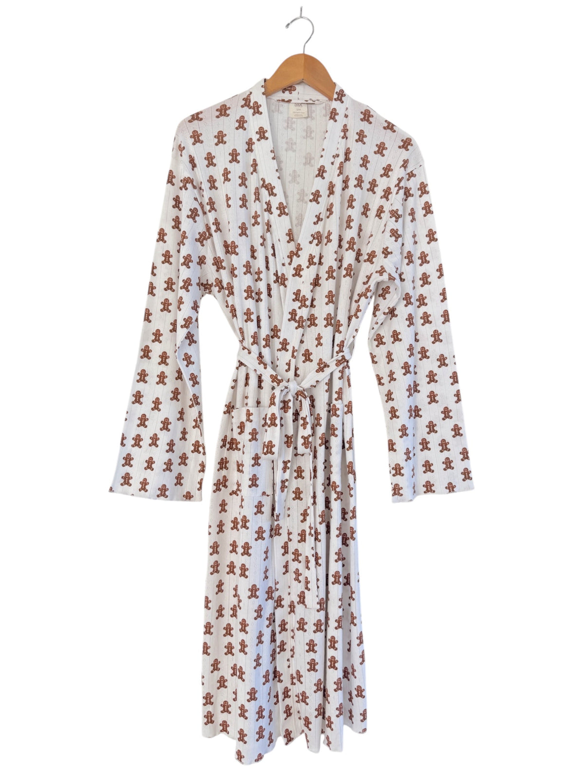 White robe with gingerbread man print, belted and hanging on a wooden hanger. Perfect for cozy occasions.