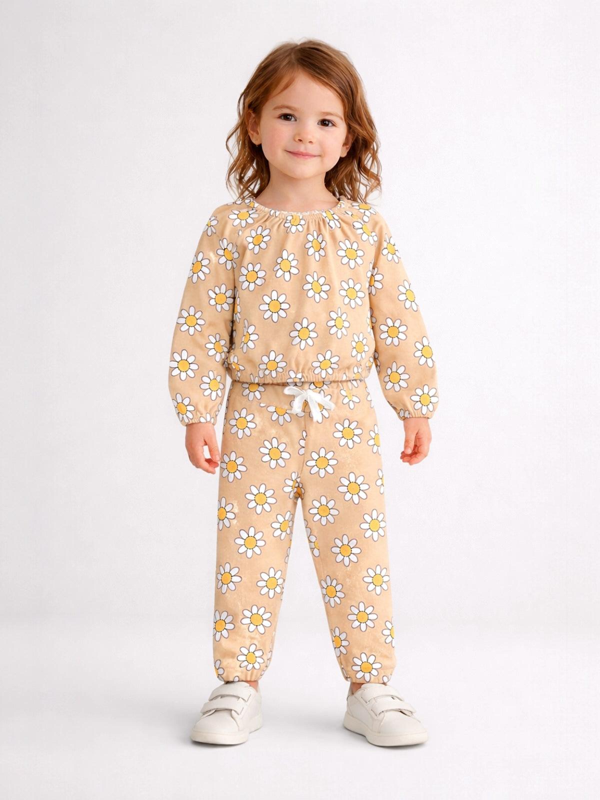 Smiling child in a floral-patterned outfit with sneakers, standing against a light background.