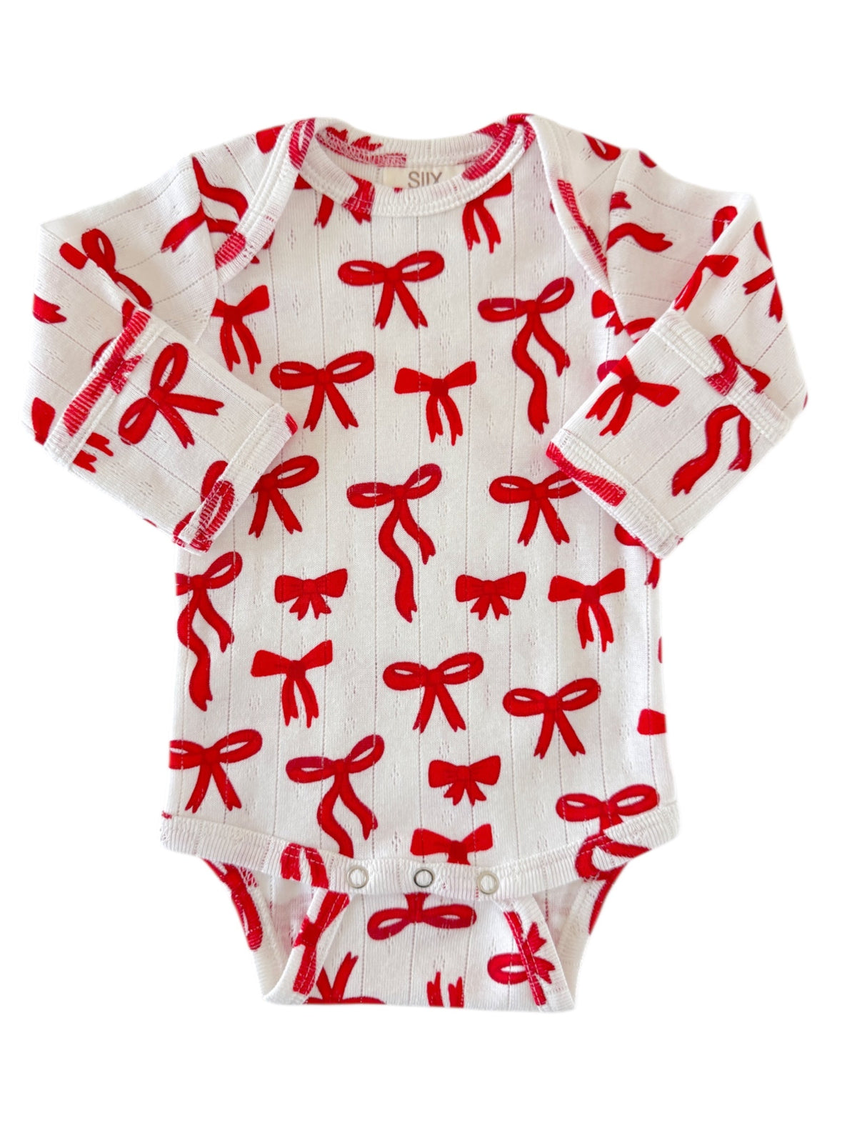 White onesie with red bows pattern, featuring long sleeves and snap closures at the bottom.