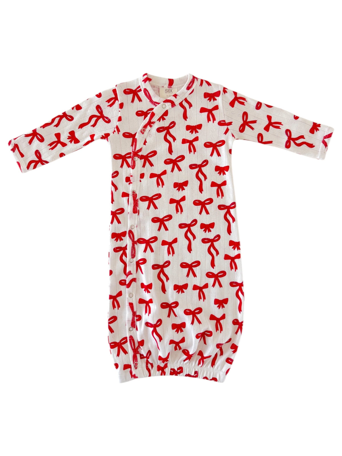 White baby gown with red bow print, featuring long sleeves and snap closures at the front.