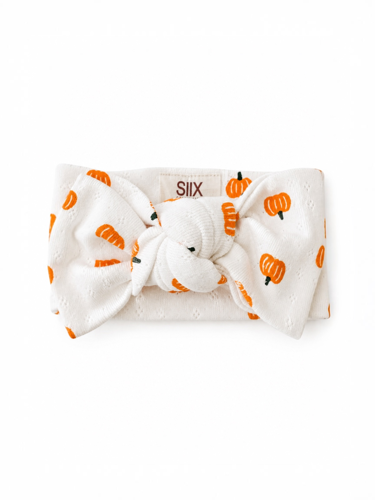 White headband with orange pumpkin print and a knot at the center, brand label visible on the back.