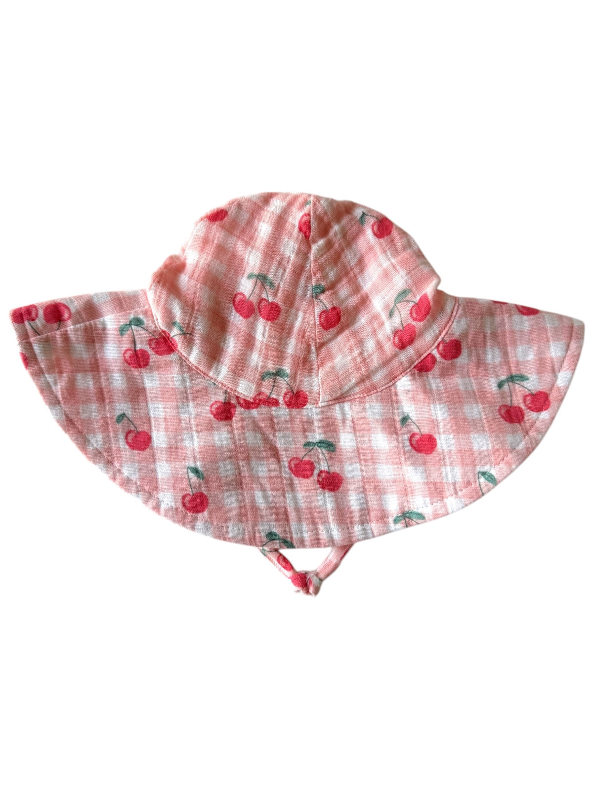 Children's sun hat with cherry print on a pink gingham background, featuring a wide brim and adjustable straps.