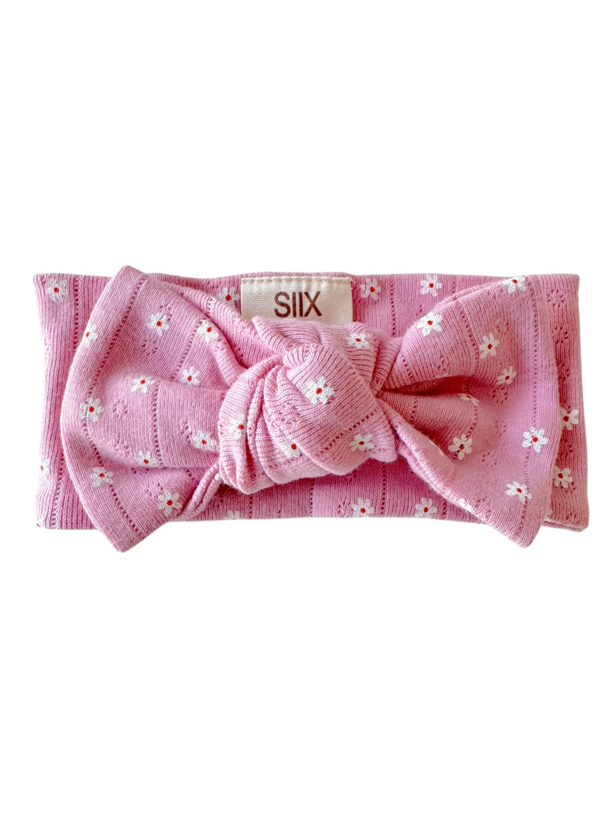 Pink headband with a knot detail and floral pattern, featuring a label that reads