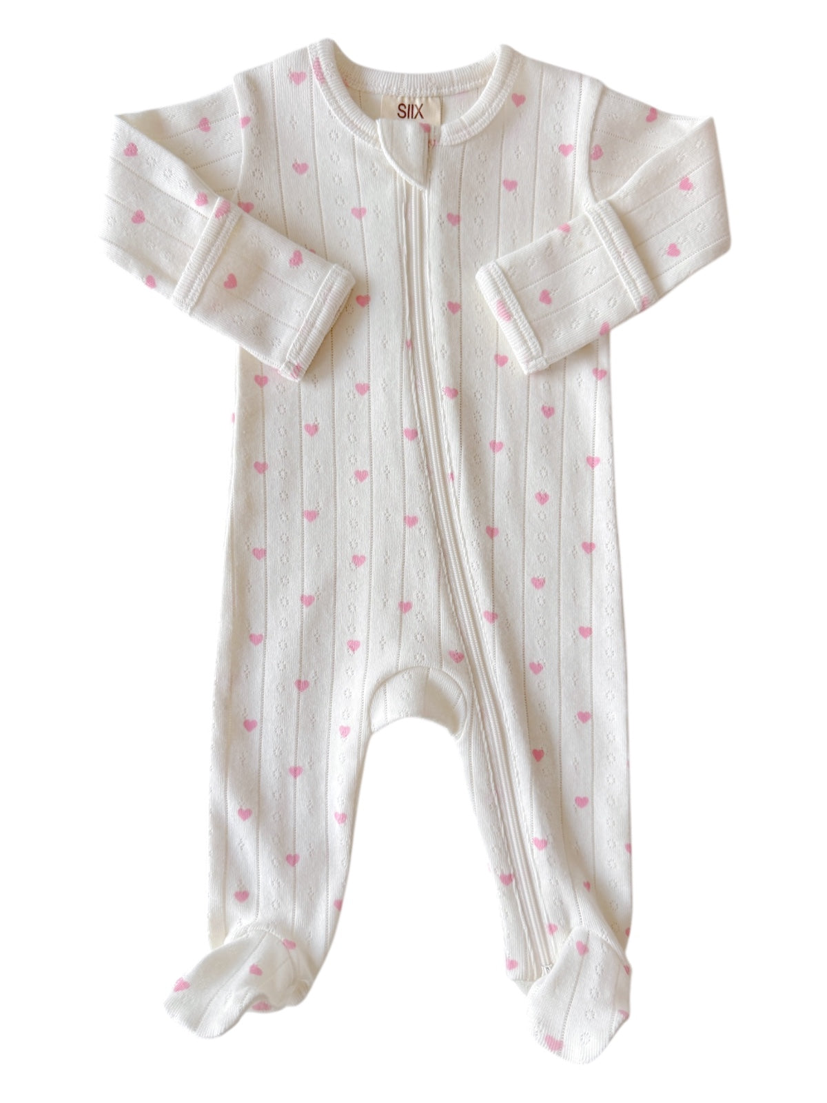 White baby onesie with pink heart patterns and a front zipper, featuring long sleeves and footed legs.