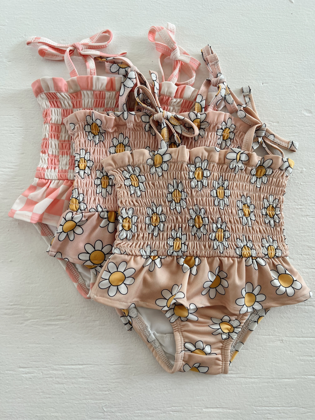 Three colorful swimsuits with floral patterns laid out on a white surface.