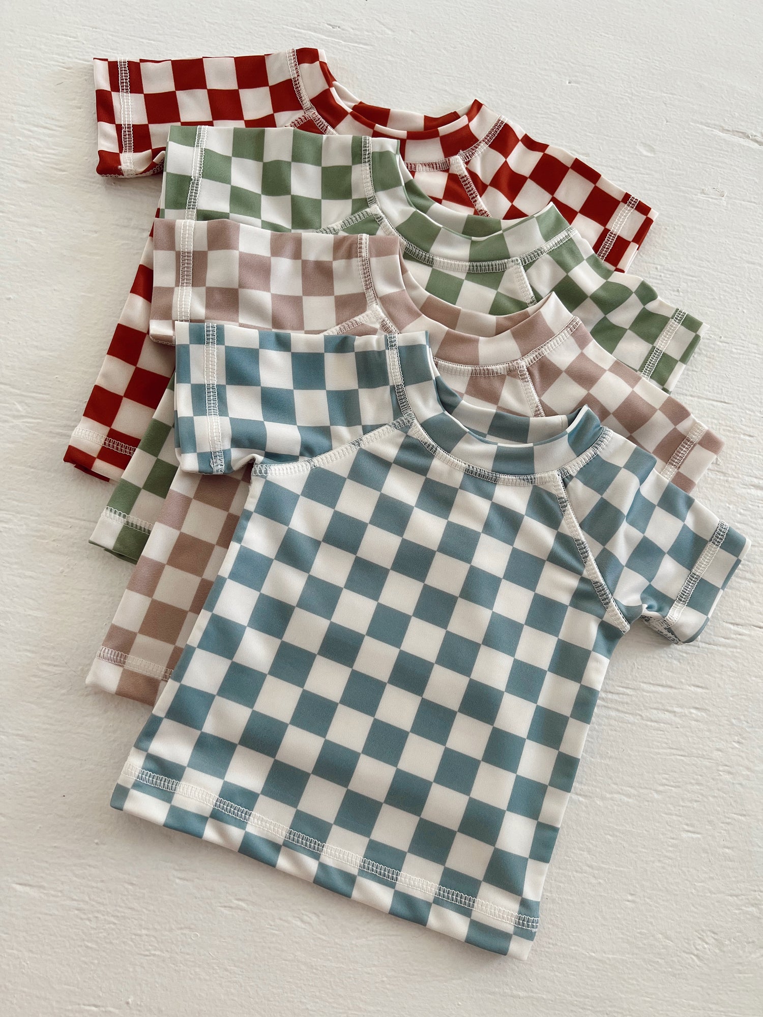 Colorful checkered shirts in red, green, blue, and brown arranged neatly on a light background.