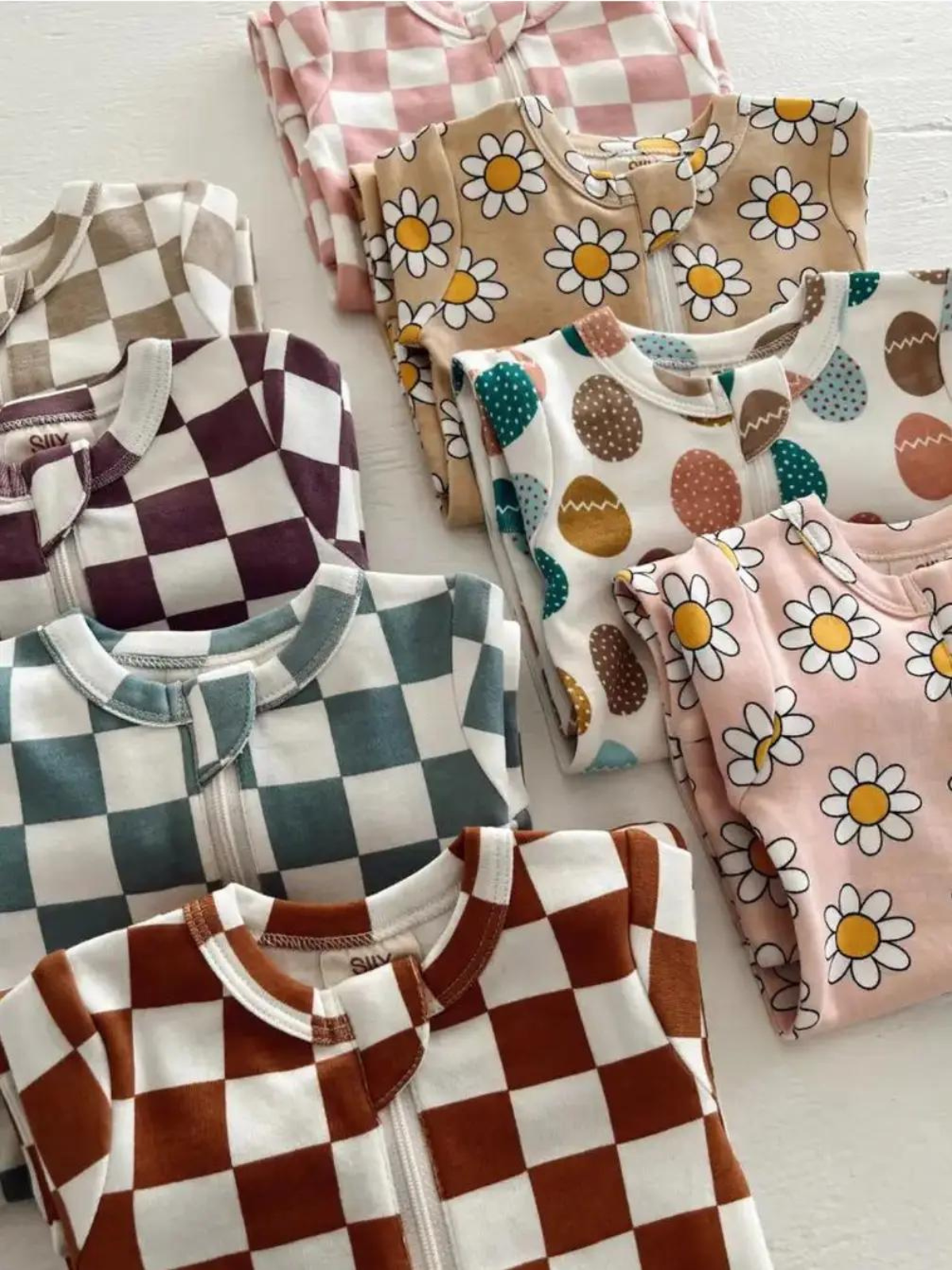 Colorful children's pajamas with various patterns, including checks, daisies, and Easter eggs, neatly folded.