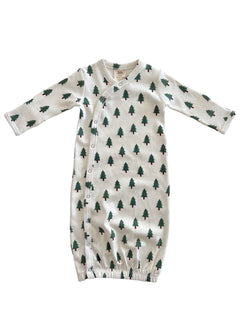Infant gown with green tree print on white fabric, featuring long sleeves and snap closures.