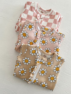 Three baby outfits featuring pink checkered and floral prints stacked on a white surface.
