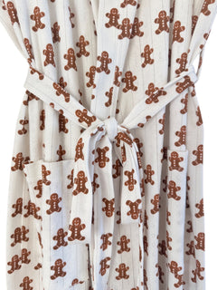White robe with gingerbread man print, featuring a tied waist and pockets. Ideal for festive comfort.