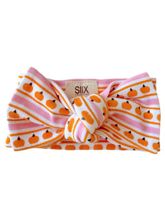 Pumpkin-patterned headband with pink and white stripes, featuring a knot design at the front. 