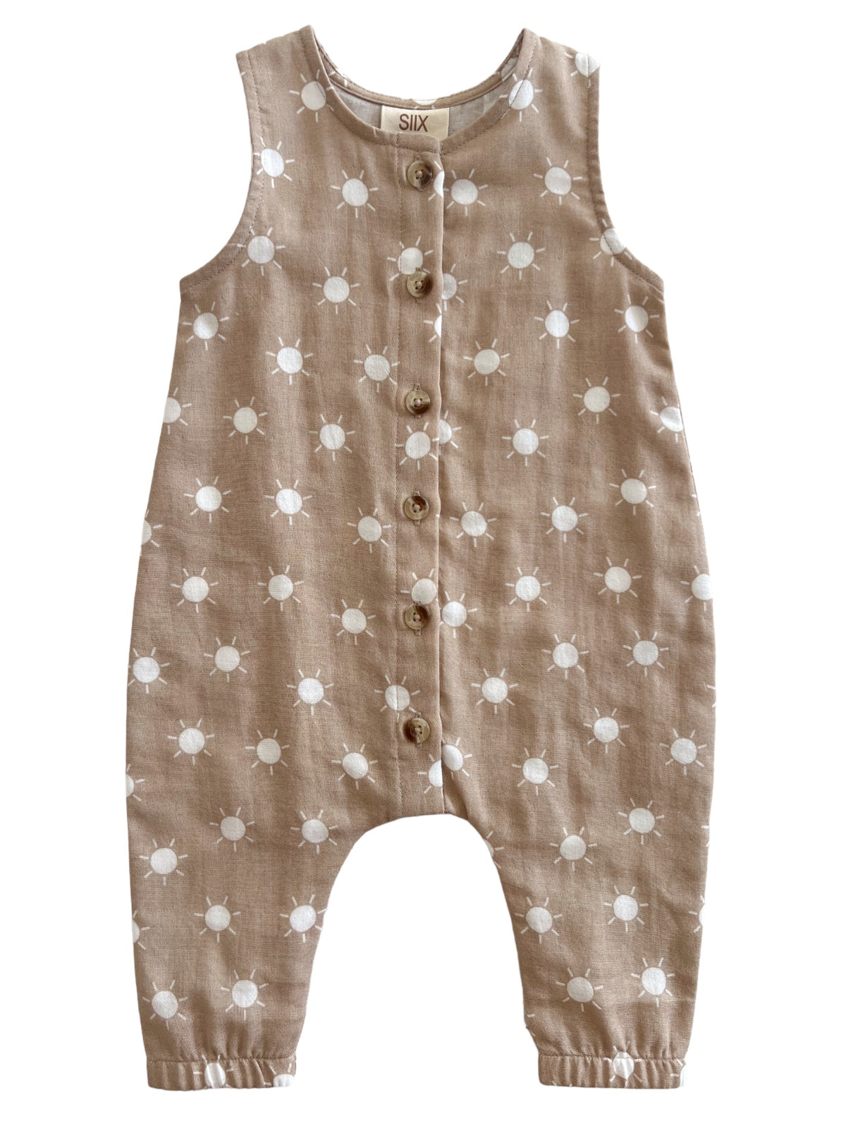 Tan children's romper with white sun patterns and wooden buttons down the front.