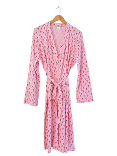 Pink robe with red pattern, long sleeves, and a tie closure, hanging on a wooden hanger.