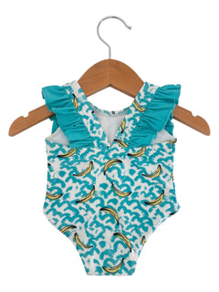 A teal ruffled swimsuit with a banana print hanging on a wooden hanger.