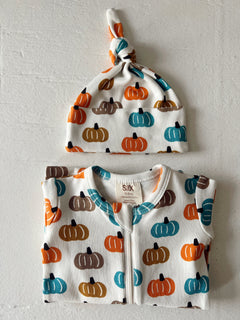 Infant clothing set featuring a pumpkin print onesie and matching knotted hat in autumn colors.