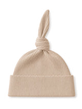 Beige ribbed knit hat with a knotted top and a folded brim, ideal for casual wear.