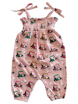 Pink jumpsuit with golf cart pattern and tie straps, perfect for casual outdoor play.