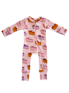 Pink onesie with a dessert pattern featuring various cake slices and whipped cream.