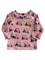 Pink long-sleeve shirt with a playful golf cart pattern and golf balls. Ideal for kids.