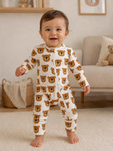 Smiling baby in bear-print onesie standing on a rug in a cozy, beautifully designed room.