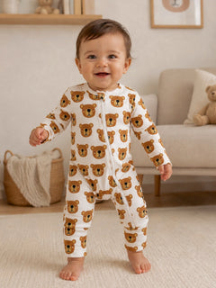 Smiling baby in bear-print onesie standing on a rug in a cozy, beautifully designed room.