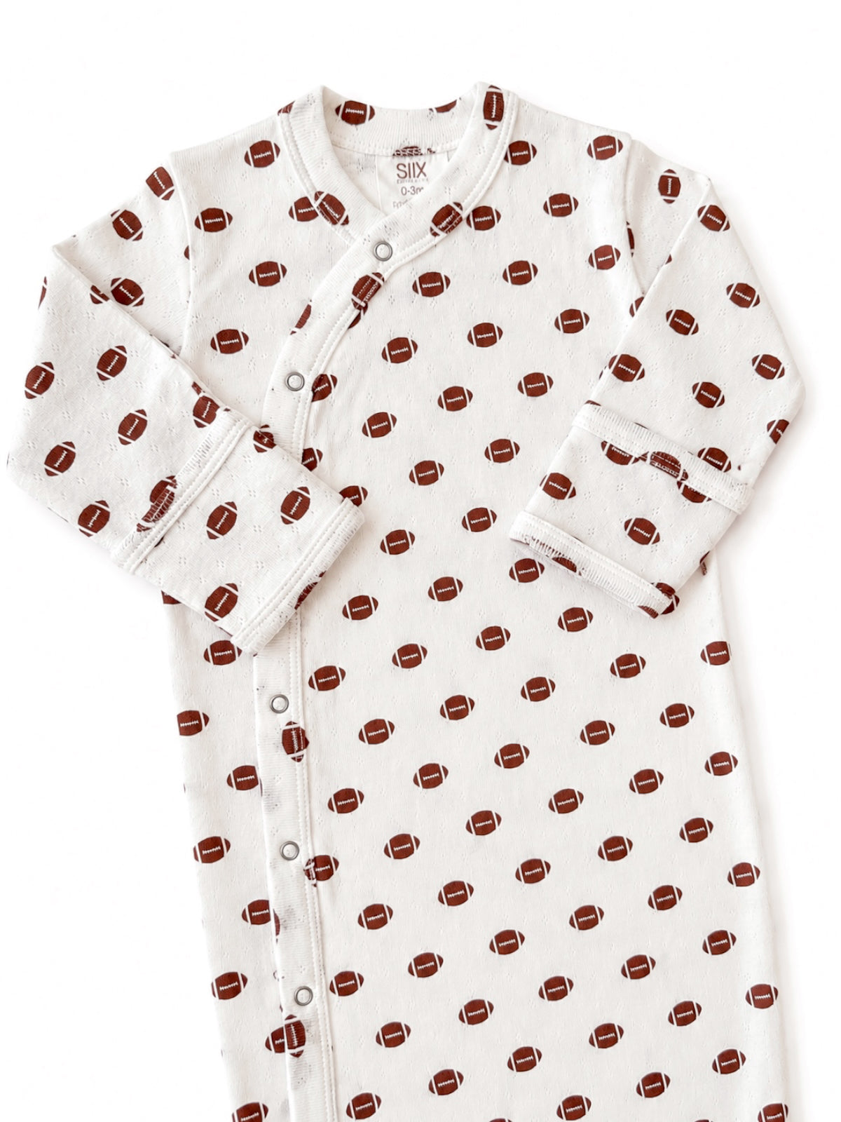 White baby onesie with a football pattern and snap closures, sized for infants 0-3 months.