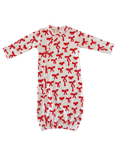 White baby gown with red bow print, featuring long sleeves and snap closures at the front.