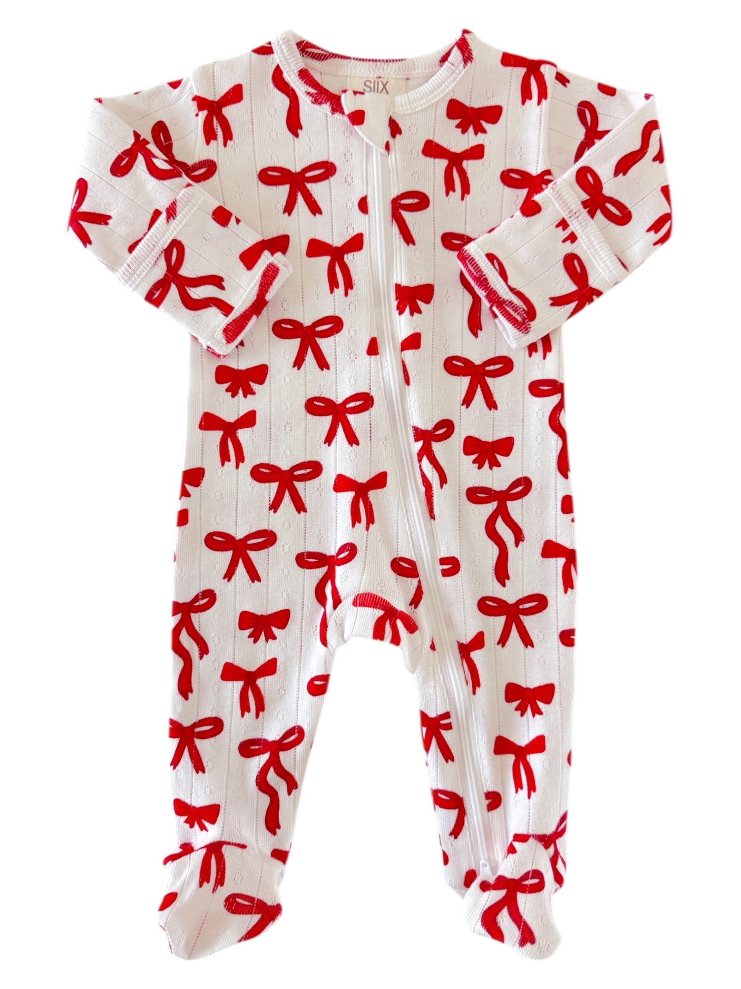 White baby onesie with red bow pattern and long sleeves, featuring snap buttons down the front.