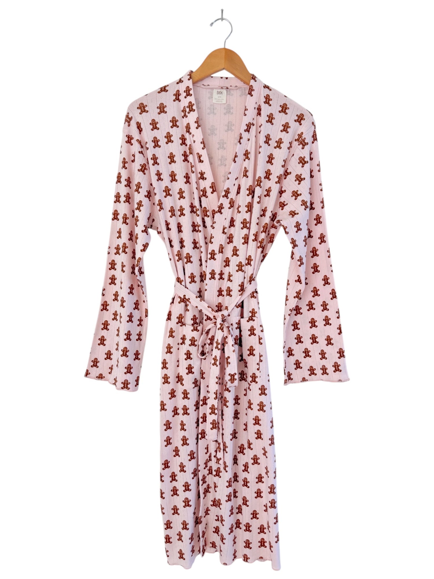 Pink robe with gingerbread man print, featuring long sleeves and a tie belt, hanging on a wooden hanger.