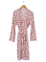 Pink robe with gingerbread man print, featuring long sleeves and a tie belt, hanging on a wooden hanger.
