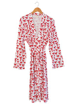 White robe featuring a playful red bow print, hung on a wooden hanger.