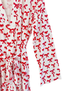 White robe with red bow pattern, featuring a tie at the waist and long sleeves.