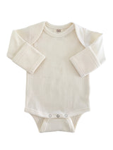 Cream-colored baby bodysuit with long sleeves and snap closures at the bottom. Soft ribbed texture.