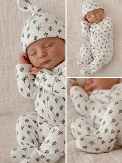 Newborn baby in cactus-patterned outfit and hat, peacefully sleeping on a textured blanket.