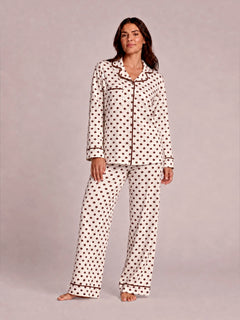 Woman in polka dot pajamas poses confidently against a light background. Casual, cozy sleepwear fashion.