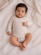 Baby in striped onesie lying on soft blanket, looking at the camera with curious expression.