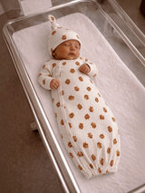 Newborn baby sleeping in a cozy, floral-patterned swaddle in a hospital crib.