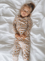 Young child in floral pajamas lying on a white blanket, smiling at the camera.
