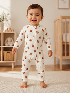 Smiling toddler in a floral onesie stands in a bright, cozy nursery. Natural light highlights playful decor.