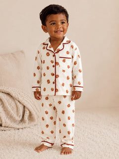 Smiling child in floral pajamas stands on a soft rug, exuding warmth and joy.