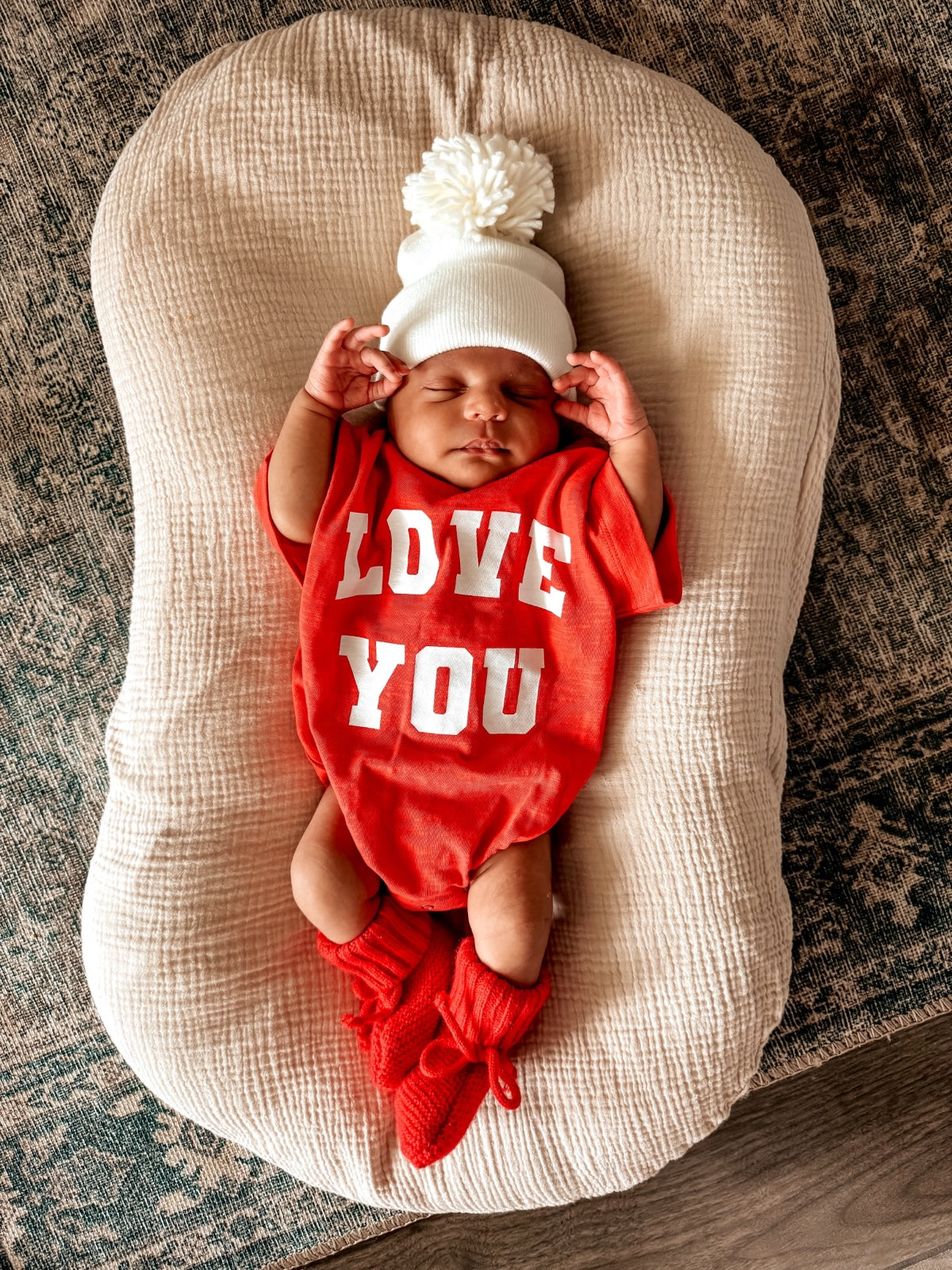Infant lying on a cushioned surface, wearing a red 