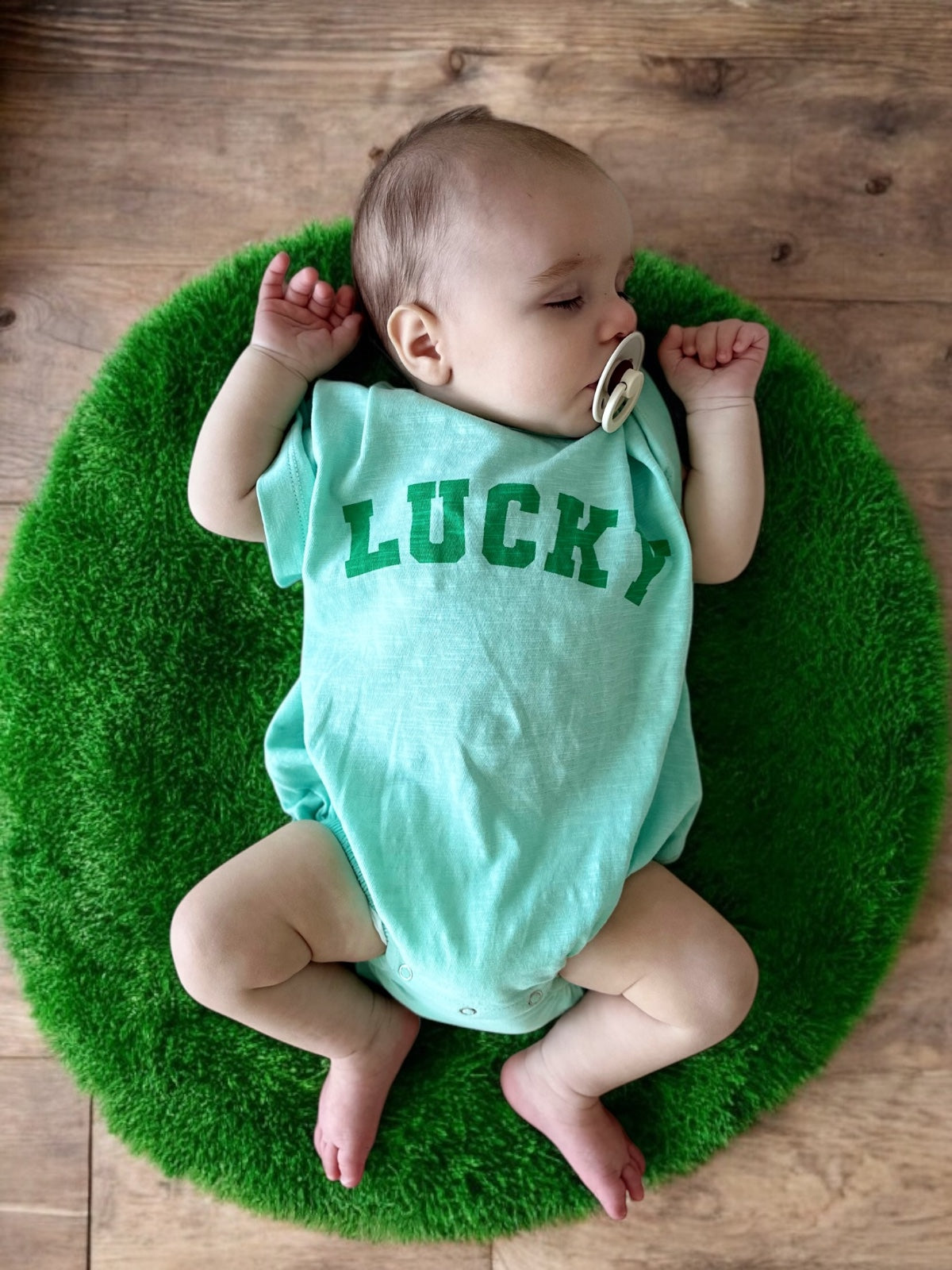 Infant wearing a mint green onesie with 