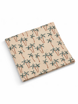 Beige napkin with a repeating pattern of green palm trees and brown trunks. Perfect for tropical-themed events.