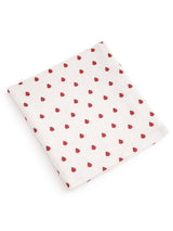 White fabric with a pattern of small red dots, folded neatly on a flat surface.