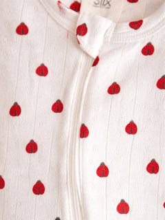 White fabric with small red ladybug patterns, featuring a zipper closure at the front.