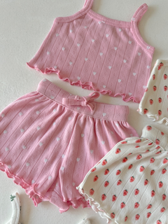 Pink heart-patterned crop top and matching shorts, alongside a white floral-patterned outfit.