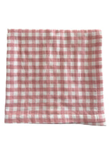 Pink and white checkered fabric laid flat, showcasing a classic gingham pattern. Ideal for home decor or crafting.