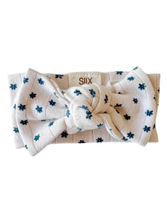 White headband with a large bow and dotted floral pattern in blue, labeled with brand name "SIIX."