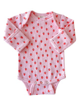 Light pink baby onesie adorned with red strawberries, featuring long sleeves and snap closures at the bottom.